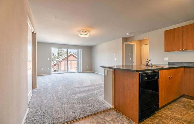 A kitchen with a black dishwasher and wooden cabinets.