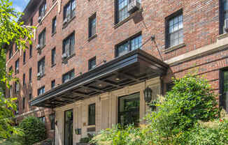 the front of a brick building with steps and plants