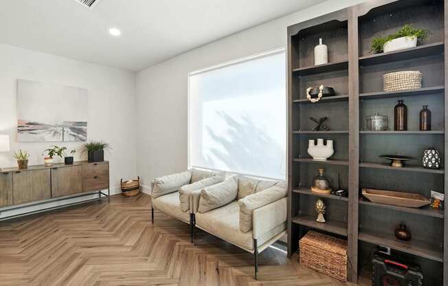 A living room with a couch, a shelf, and a painting on the wall.