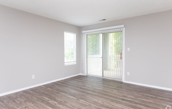 an empty living room with wood floors and a sliding glass door