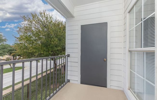 the balcony of a home with a black door and a metal railing