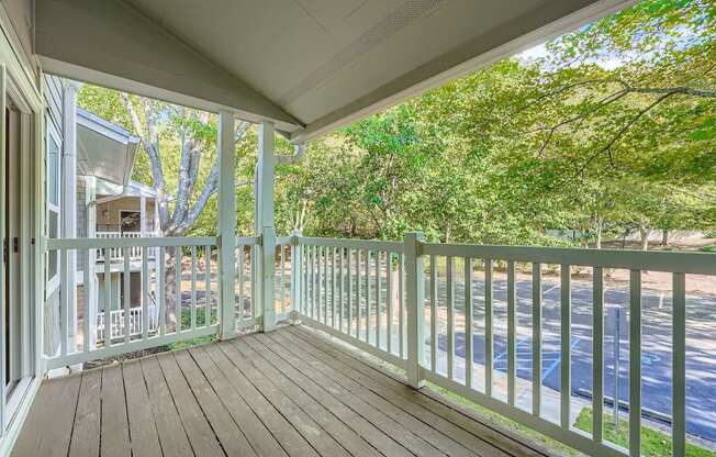 A white balcony with a wooden floor and a white railing.