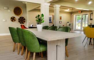 a large wooden table with green chairs in a room with white walls