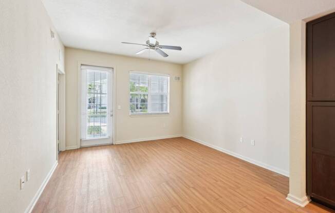 A room with a ceiling fan and wooden floors.