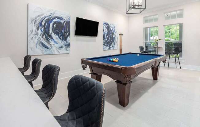 A pool table is surrounded by chairs in a room.