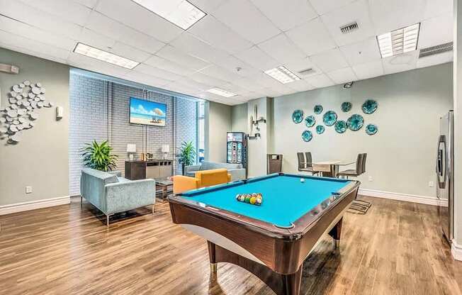 A pool table is in the middle of a room with a TV on the wall.