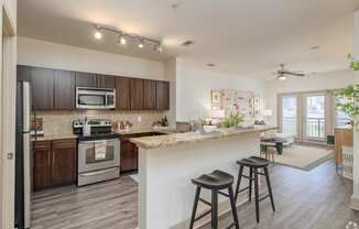 an open kitchen and living room with a bar and stools