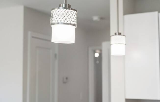 three lights hanging from a ceiling in a white kitchen