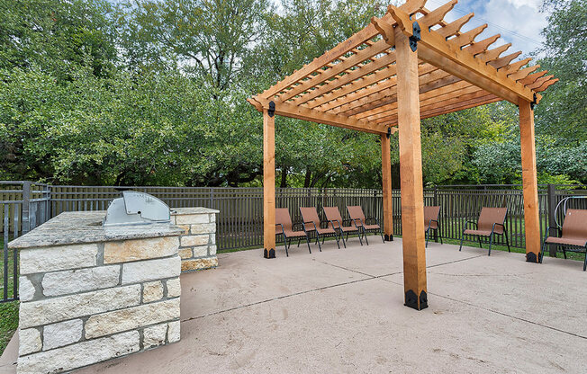 a patio with a stone fireplace and a wooden pavilion at The Broadwater at Salado Creek, San Antonio
