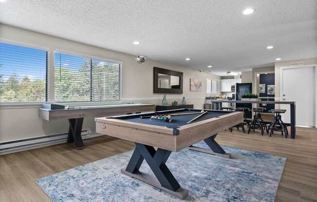 A pool table in a room with a view of trees outside the window.