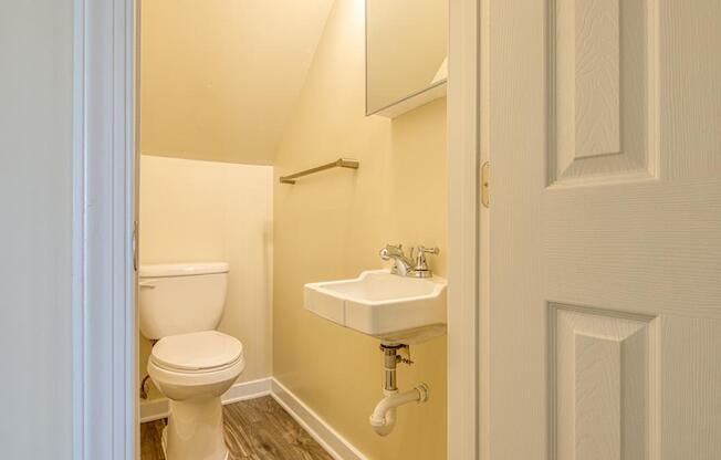 A white toilet sits next to a white sink in a small bathroom.