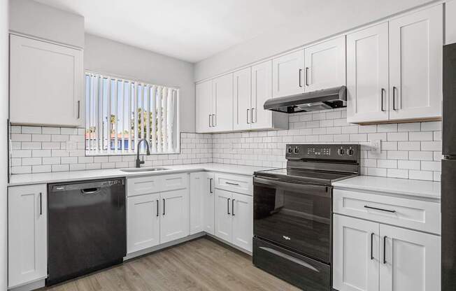 A kitchen with white cabinets and black appliances.
