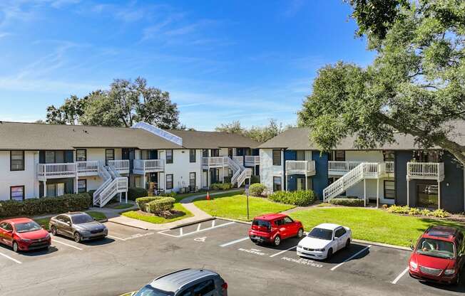an exterior view of an apartment building with cars parked in a parking lot