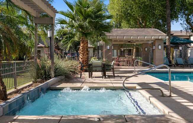 A pool with a waterfall and a hot tub in a backyard.