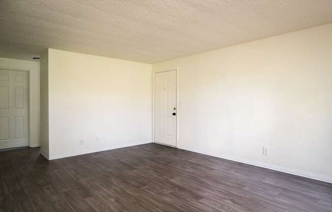 an empty living room with white walls and wood floors