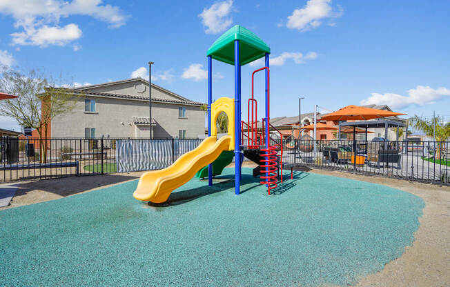A playground with a yellow slide and a blue and green top.