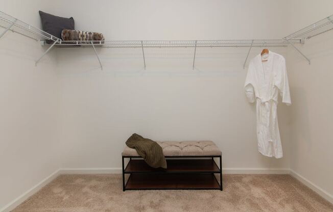 a white room with a white robe hanging on the wall and a white bench in the middle