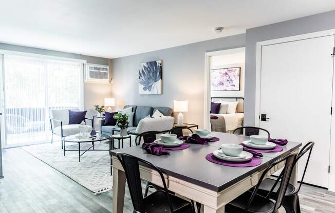 a living room with a dining room table and chairs and a couch and chair in the background
