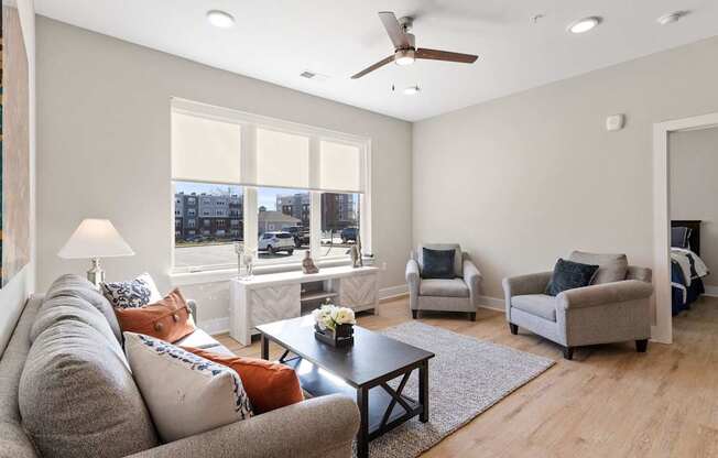 Living room of model unit in Park View Greer Apartments in Greer, SC with a couch, coffee table, two loveseats, three windows and LVT flooring.