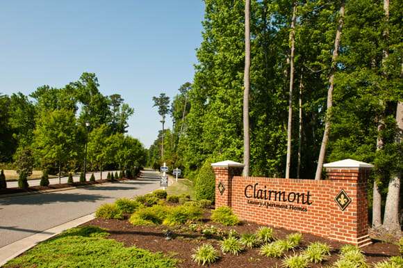 Tree-lined street with Clairmont Apartments sign leading into the community