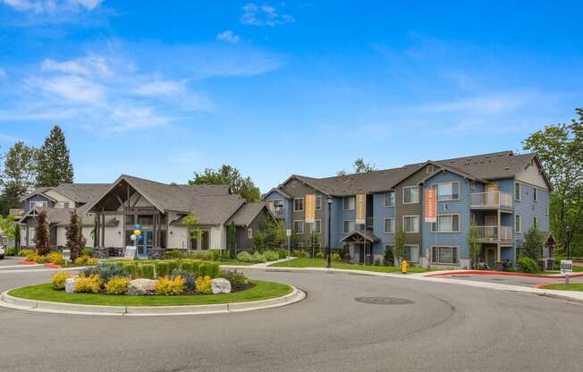 Entrance Round-About with Blue and Gray Apartment Exteriors, Road, Plants and Grass Covered Center