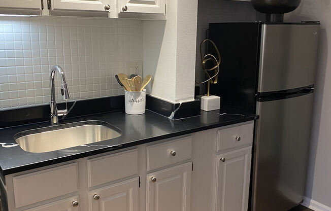 a kitchen with white cabinets and a sink and a refrigerator