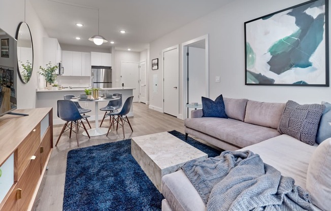 Modern open floor plan living room and kitchen in a luxury apartment rental at The Mint Rahway, featuring sleek furniture and decor.