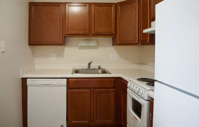 Kitchen with wood cabinets, dishwasher, sink, oven, and refrigerator. At Highland Towers in Southfield