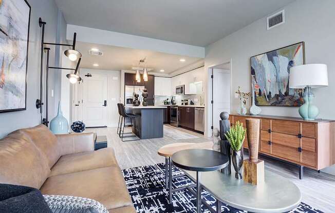 A living room with a tan couch and a black and white rug.