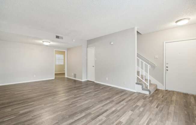 the living room and dining room of an apartment with wood flooring