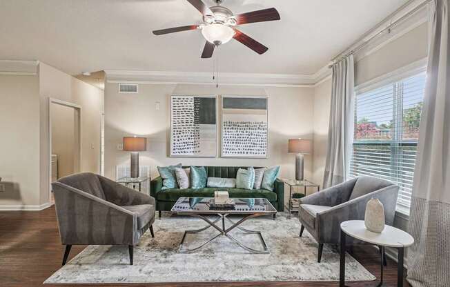 A living room with a green couch, grey armchair, and a white side table.