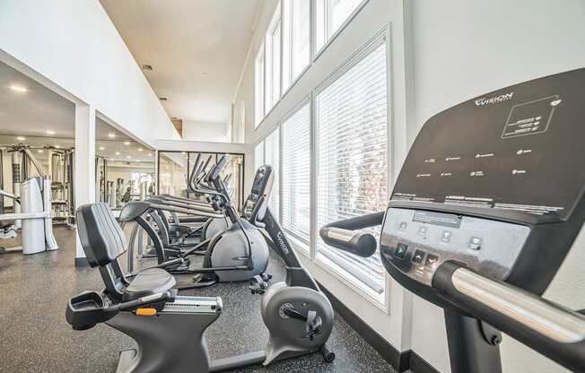 a gym with treadmills and other exercise equipment in a building with large windows