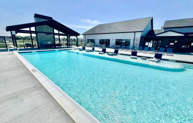A large outdoor swimming pool with a concrete edge and a white concrete pool deck.