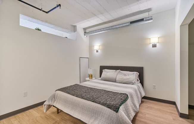 a bedroom with a bed and white walls and wood floors