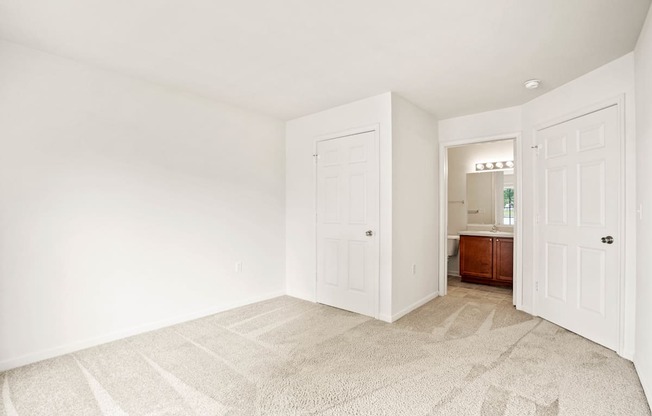 A room with a carpeted floor and two doors.