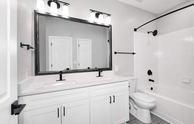 Bathrooms with quartz countertops, dual vanities and framed mirrors