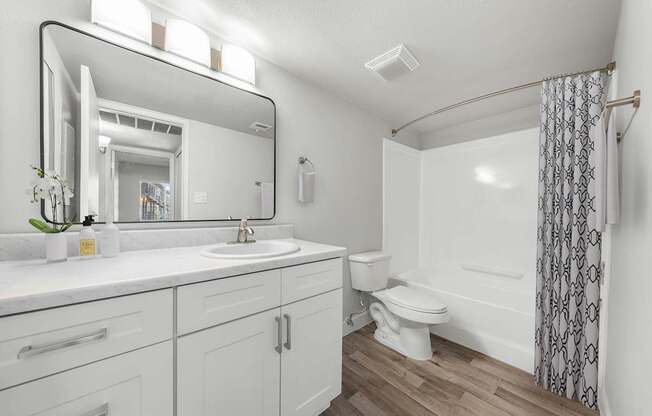 A white bathroom with a sink, toilet, and a shower.