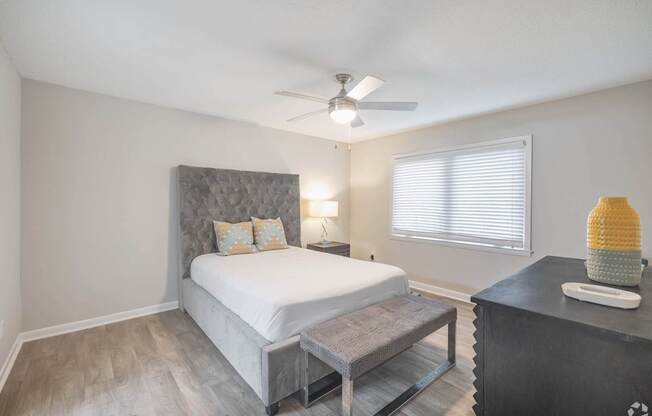 A bedroom with a bed, nightstand, and a ceiling fan.