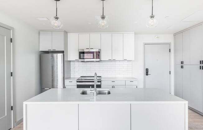 a white kitchen with white cabinets and stainless steel appliances at The Commonwealth Building, Pittsburgh, Pennsylvania
