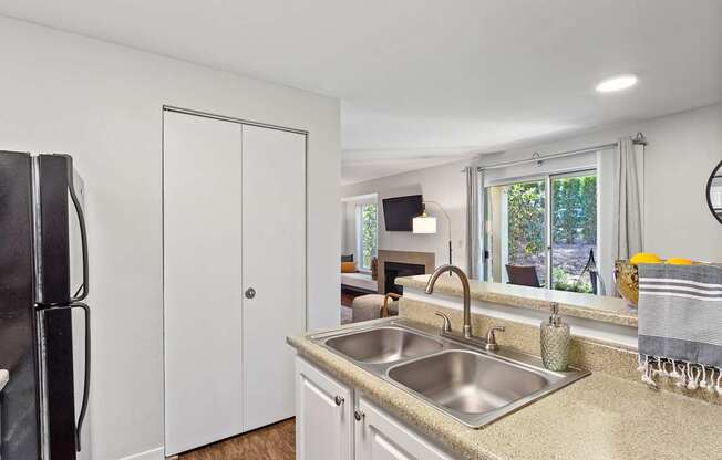 A kitchen with a sink, refrigerator, and a window.