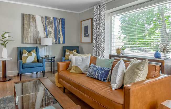 a living room with a brown leather couch and blue chairs