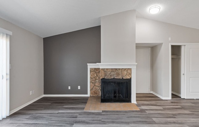 an empty living room with a fireplace and grey walls