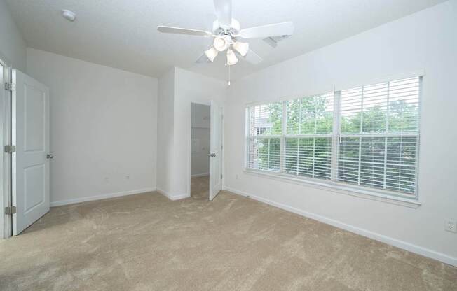 A room with a ceiling fan and a window with blinds.