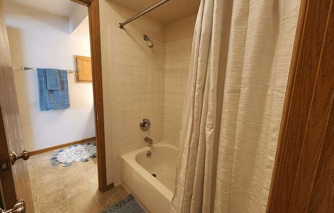 A bathroom with a white tub and a white shower curtain.