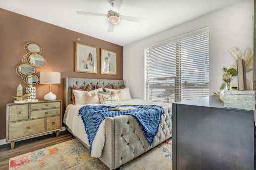 A bedroom with a large bed, a dresser, and a ceiling fan.
