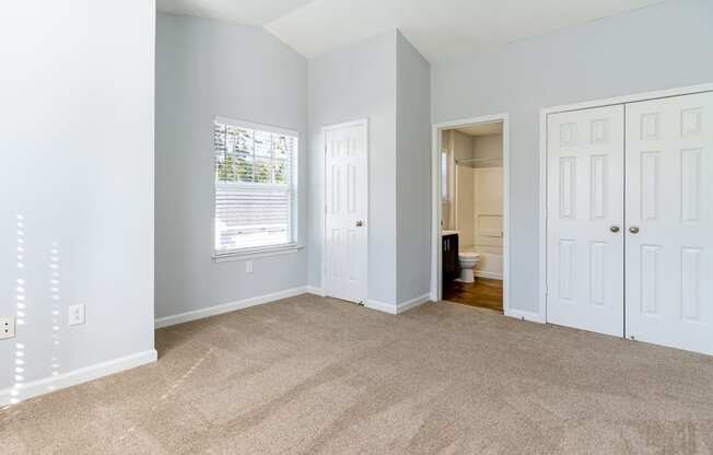 an empty living room with carpet and a door to a bathroom
