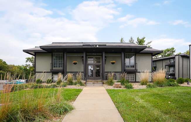 A modern house with a grey roof and a glass door.