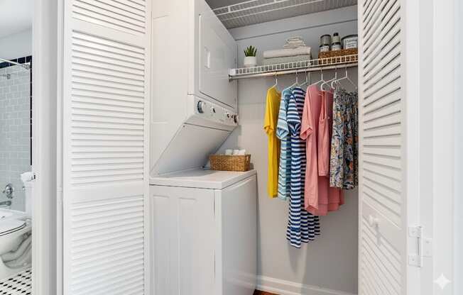 A white laundry room with a washer and dryer and clothes hanging up.