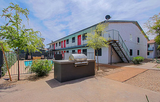 a backyard with a grill and a pool in front of a white building with red and green