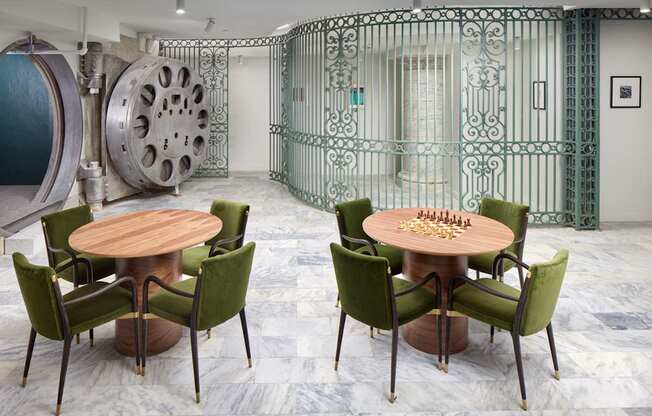 A room with a table and chairs and a large bank vault door.